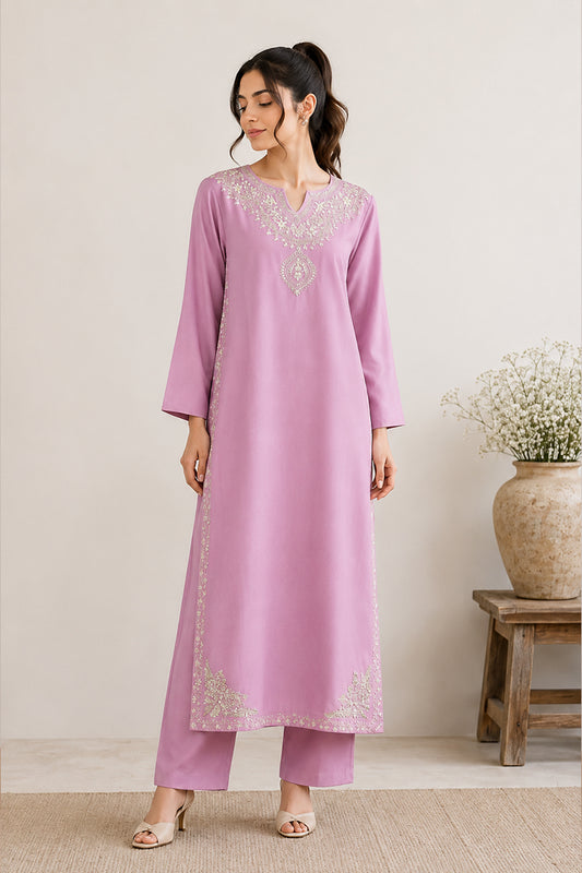 A woman models a lavender purple kurta and matching trousers set with intricate silver embroidery around the neckline and hem, standing in a neutral indoor setting.