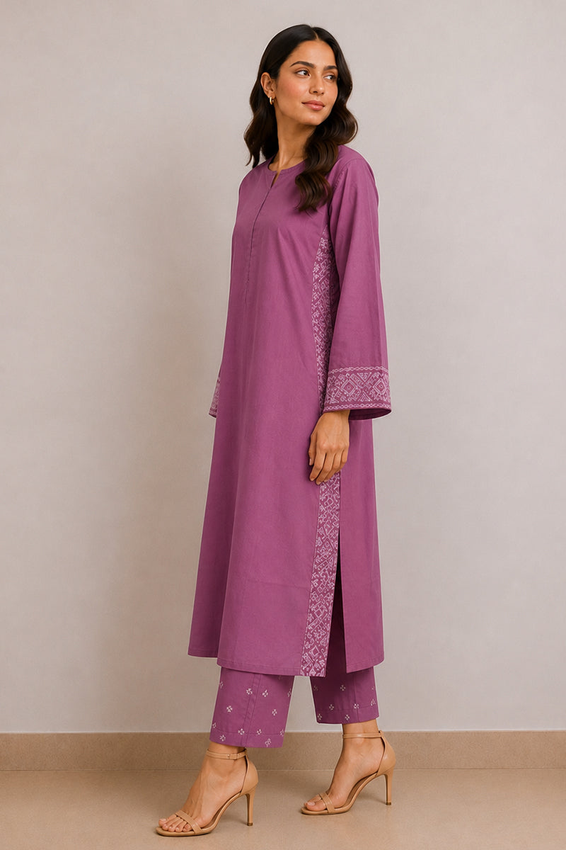 A woman modeling a purple kurta and matching pants set with white embroidered details on the sleeve cuffs and side panels, standing against a neutral beige studio background.