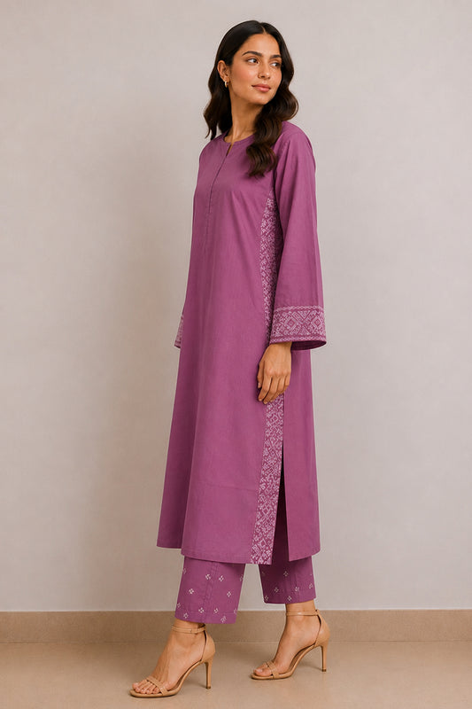 A woman modeling a purple kurta and matching pants set with white embroidered details on the sleeve cuffs and side panels, standing against a neutral beige studio background.