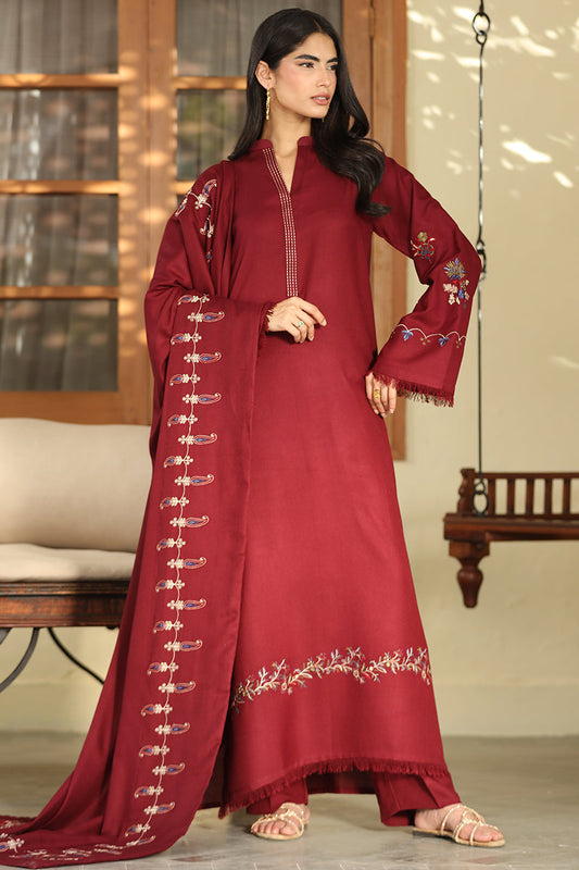 A woman models a deep maroon red ethnic suit set featuring a long kurta with gold embroidery, matching flared sleeves, and a coordinating dupatta with gold paisley patterns, set against a warm indoor background.