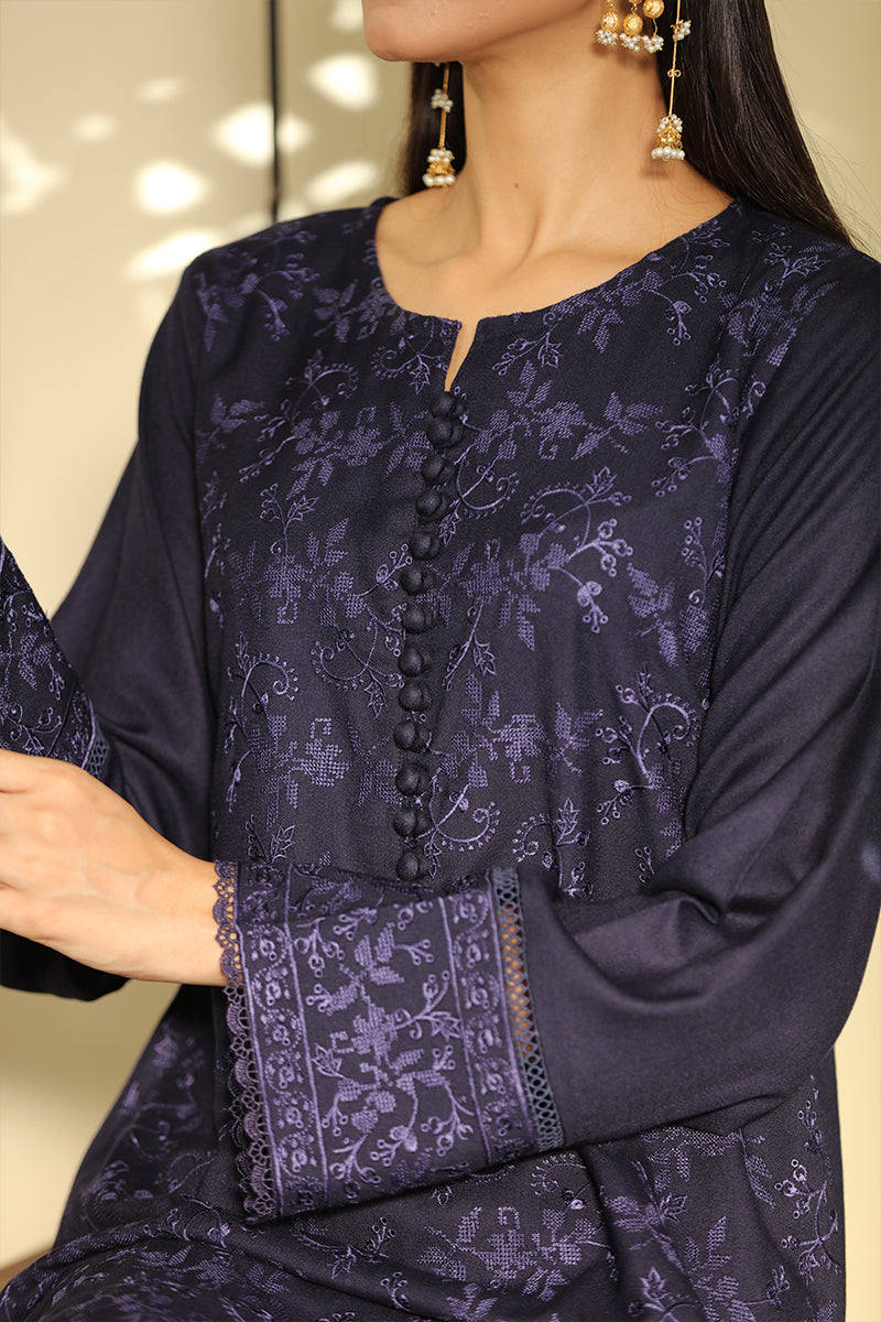 A close-up of a woman wearing a dark purple embroidered tunic with floral patterns, a split neckline with decorative buttons, and long sleeves with lace-trimmed cuffs.